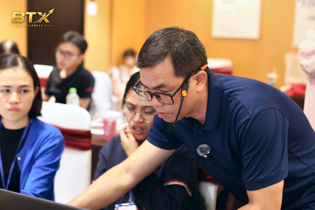 Nguyễn Trương Tuyến cúi xuống kèm từng học viên tại bàn, khoá BTS